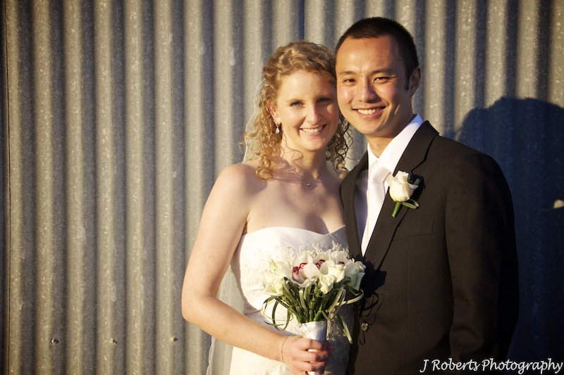 Couple at sunset with corrugated iron wall behind - wedding photography sydney